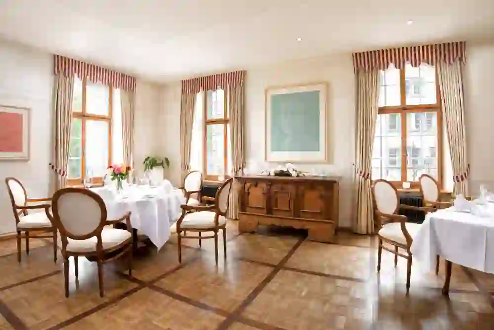 The picture shows a bright, friendly restaurant at Stadthaus Burgdorf with elegantly laid tables, harmoniously coordinated furniture and a large window front that conveys an inviting, relaxed atmosphere.