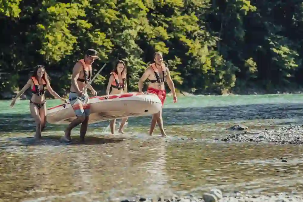 Un gruppo di quattro amici porta insieme il proprio gommone fuori dalle acque limpide dell'Aare. I loro vestiti estivi e i giubbotti di salvataggio, le risate e la piacevole stanchezza dopo una giornata sul fiume dipingono un quadro pieno di amicizia e di divertimento nel bellissimo paesaggio fluviale.