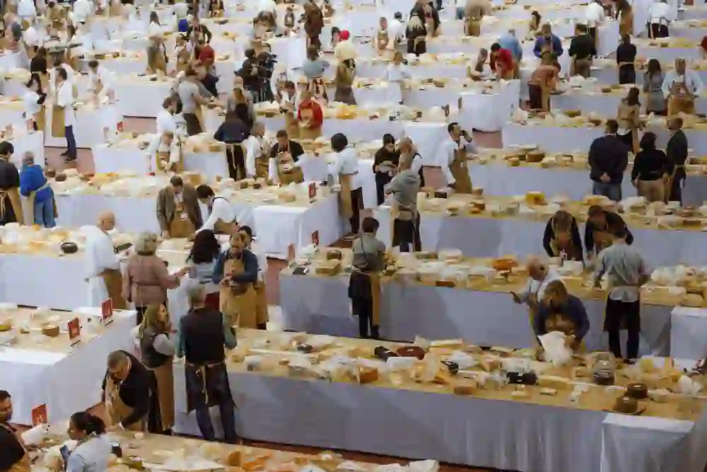 The picture shows a cheese exhibition and people marvelling at and judging the cheese as part of the World Cheese Awards