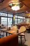 L'image montre l'intérieur d'un restaurant élégant aux tons chauds et accueillants et à l'aménagement de bon goût, qui promet une atmosphère détendue et agréable pour manger.