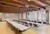 La salle donne une impression de calme, de clarté et de concentration. Les longues rangées de tables en forme de U créent une atmosphère structurée et propice au dialogue - idéale pour les réunions, les ateliers ou les séminaires. Les poutres en bois apparentes au plafond confèrent à la salle chaleur et caractère, tandis que les grandes fenêtres laissent entrer beaucoup de lumière du jour et rendent le contexte historique perceptible. Dans l'ensemble, il en résulte une interaction équilibrée entre fonctionnalité, discrétion et élégance intemporelle.