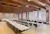 La salle donne une impression de calme, de clarté et de concentration. Les longues rangées de tables en forme de U créent une atmosphère structurée et propice au dialogue - idéale pour les réunions, les ateliers ou les séminaires. Les poutres en bois apparentes au plafond confèrent à la salle chaleur et caractère, tandis que les grandes fenêtres laissent entrer beaucoup de lumière du jour et rendent le contexte historique perceptible. Dans l'ensemble, il en résulte une interaction équilibrée entre fonctionnalité, discrétion et élégance intemporelle.
