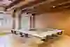 La salle donne une impression de calme, de clarté et de concentration. Les longues rangées de tables en forme de U créent une atmosphère structurée et propice au dialogue - idéale pour les réunions, les ateliers ou les séminaires. Les poutres en bois apparentes au plafond confèrent à la salle chaleur et caractère, tandis que les grandes fenêtres laissent entrer beaucoup de lumière du jour et rendent le contexte historique perceptible. Dans l'ensemble, il en résulte une interaction équilibrée entre fonctionnalité, discrétion et élégance intemporelle.