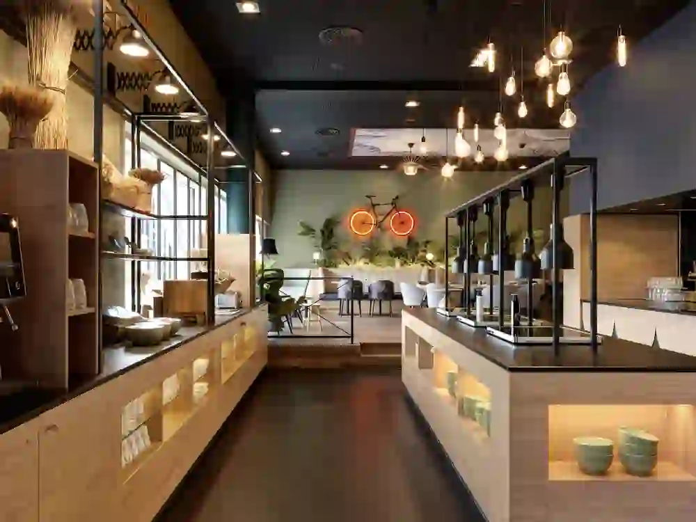 Une brasserie élégante et moderne, avec des lumières chaudes et des éléments naturels, qui crée une atmosphère confortable et accueillante pour les visiteurs.