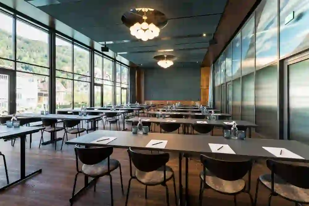 Das Bild zeigt einen hellen und geräumigen Seminarraum mit großen Fenstern, der eine produktive und klare Atmosphäre für Meetings und Bildungsveranstaltungen schafft.