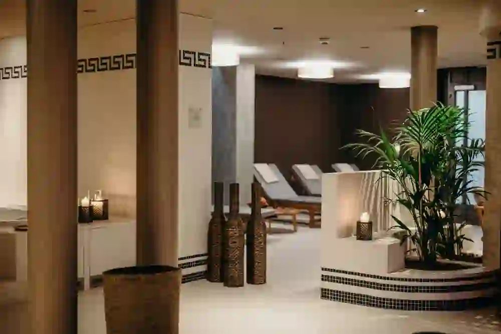 Auf dem Bild ist ein ruhiger Wellnessbereich mit sanfter Beleuchtung im Schloss Hünigen, Liegestühlen und dekorativen Elementen zu sehen, der eine Atmosphäre der Entspannung und des Wohlbefindens schafft.