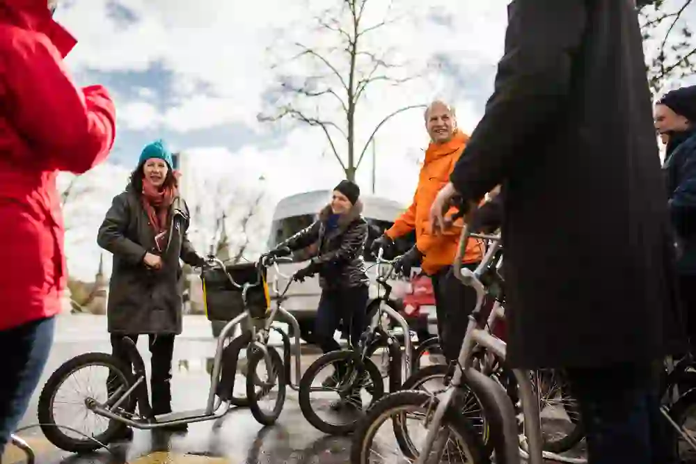 Un groupe sourit et se prépare à faire un tour de trottinette, vêtu de vestes d'hiver contre l'air frais d'une journée claire à Berne.