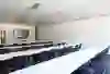 L'immagine mostra una sala conferenze moderna e luminosa, con grandi finestre che offrono una vista sul verde. I tavoli e le sedie bianche sono disposti a U. L'atmosfera chiara e luminosa favorisce la concentrazione e la creatività.