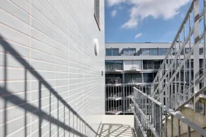 Detail der hinterlüfteten Keramikfassade mit Stahltreppe und Blick in den Innenhof des „Urban Court" in Brüssel