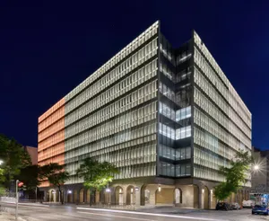 Wohn- und Geschäftshaus in Athen bei Nacht mit beleuchteter Fassade und nächtlicher Lichtinszenierung des Lamellenrasters
