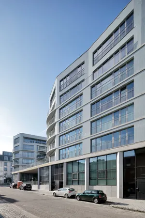 Wohngebäude „Urban Court" in Brüssel mit hellen Keramikfliesen und geschwungenen, durchlaufenden Balkonbändern