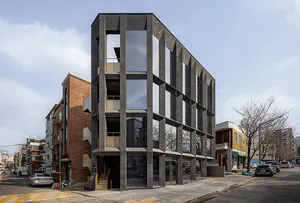 Four-story office building in Seoul with a dark textured façade and striking angled supports.