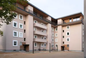 Renovated residential building with light façades, balconies, and updated architectural details.