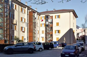 Straßenansicht eines älteren Wohngebäudes vor der Sanierung, mit heller Fassade und Holzläden.