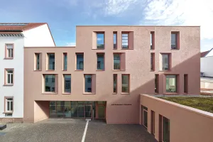 Moderner Gebäudetrakt mit großer Glasfassade und farbigen grafischen Elementen im Innenhof.