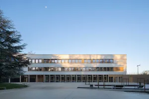 Außenaufnahme Schulneubau mit heller, gedämmter Sto-Putzfassade und braunem Sockel