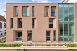 Moderner Gebäudetrakt mit großer Glasfassade und farbigen grafischen Elementen im Innenhof.