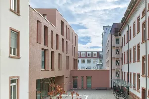 Moderner Gebäudetrakt mit großer Glasfassade und farbigen grafischen Elementen im Innenhof.