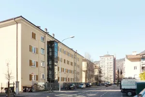 Straßenansicht eines älteren Wohngebäudes vor der Sanierung, mit heller Fassade und Holzläden.