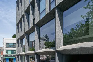 Viergeschossiges Bürogebäude in Seoul mit dunkler, strukturierter Fassade und markanten, schrägen Stützen.