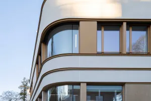 Close-up Schulneubau, geschwungene Putzfassade von Sto mit Metallkanten und Fenstern