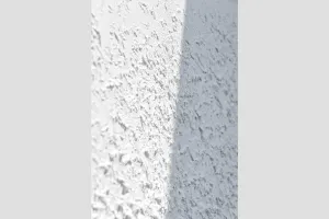 Closeup eines weißen Putzmuster mit Schatten im Hochformat