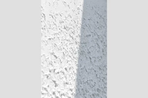 Closeup eines weißen Putzmuster mit Schatten im Hochformat
