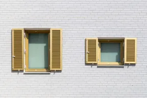 Gelungener Kontrast: weiße Riemchen und goldfarbene Fensterläden.