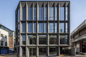 Viergeschossiges Bürogebäude in Seoul mit dunkler, strukturierter Fassade und markanten, schrägen Stützen.