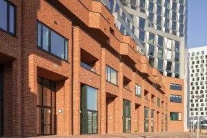 „De Puls“ Gebäudekomplex mit Fassade in Backsteinoptik und Metallrasterfassade