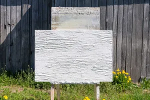 Weißes Putzmuster im Querformat auf Musterständer, auf Blumenwiese, vor Berghütte