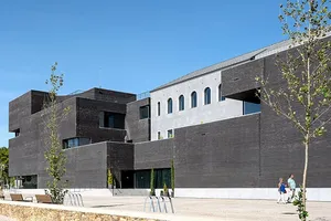 Trofa Town Hall's contrast between the old and new is evident in the materials chosen - the restored original building in fine-grained grey render with a glazed top coat; the new building volumes in a bold envelope of dark bricks.