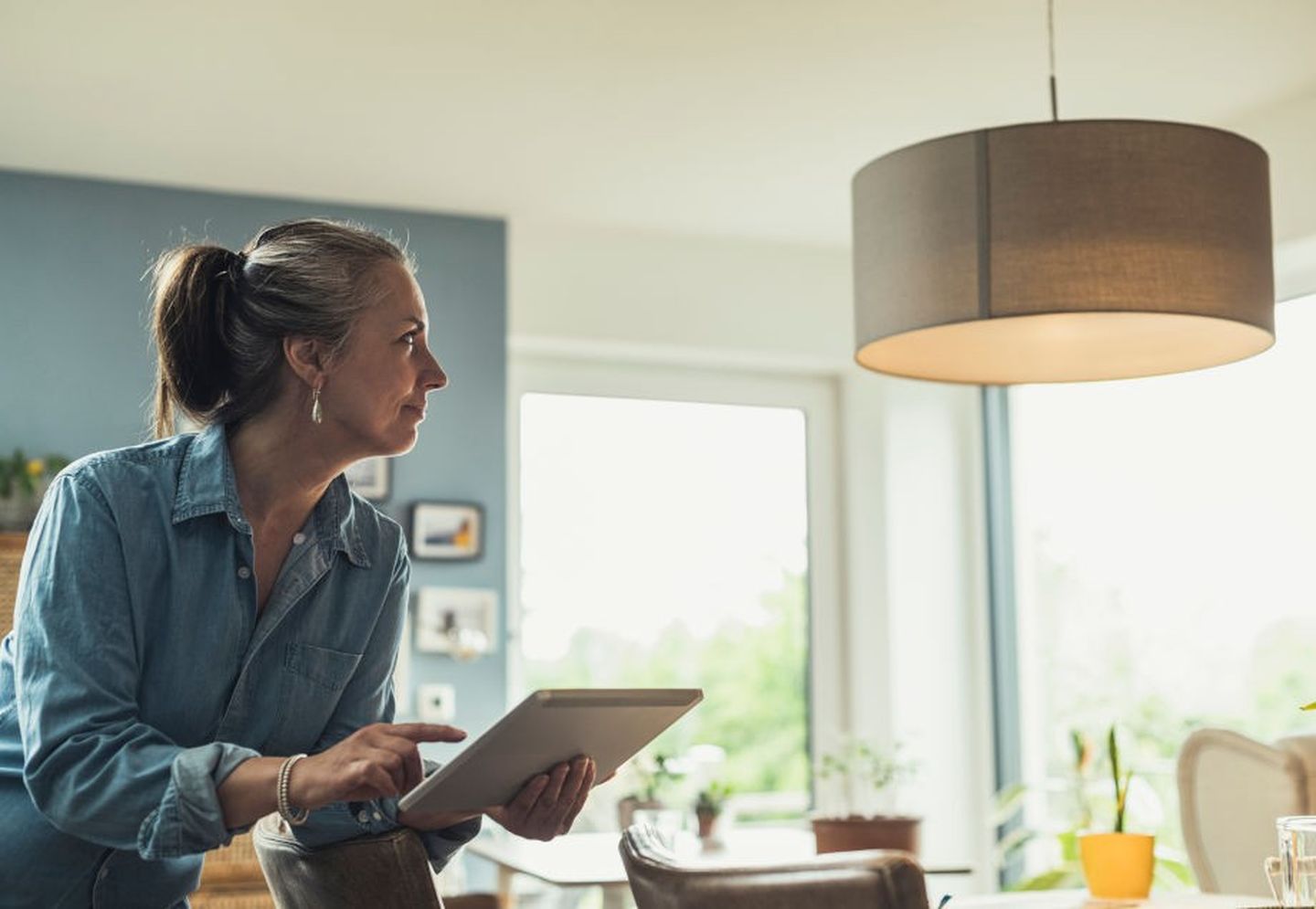 Eine Frau regelt über Smart Home ihre Lampen. 