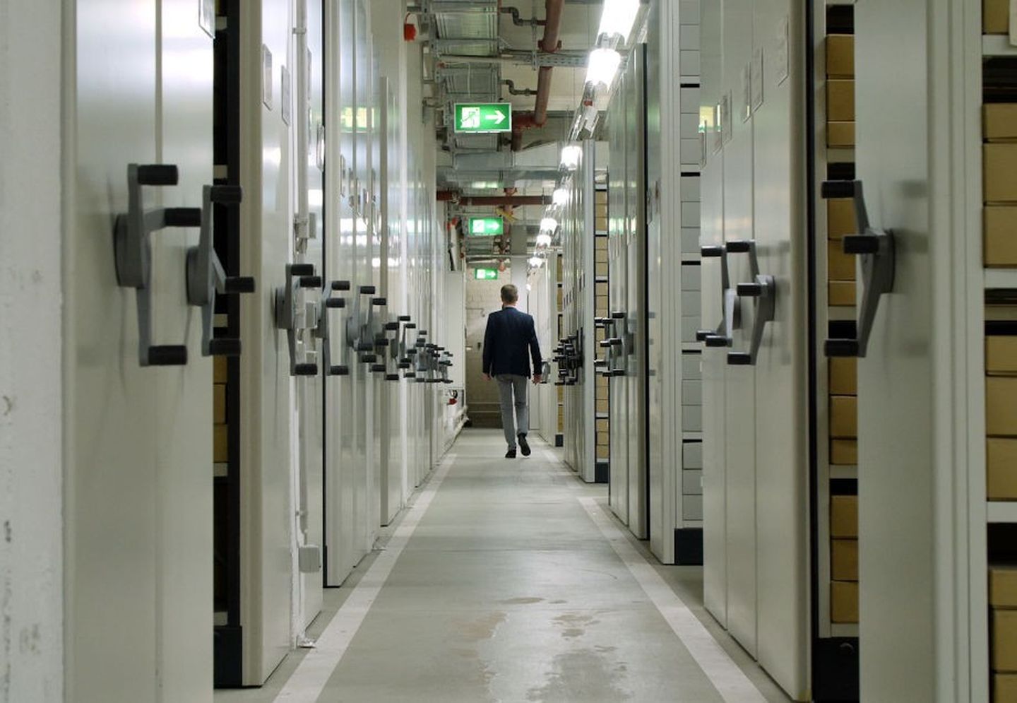 Leiter des Stadtarchivs läuft durch die Archiv- und Aktenregale