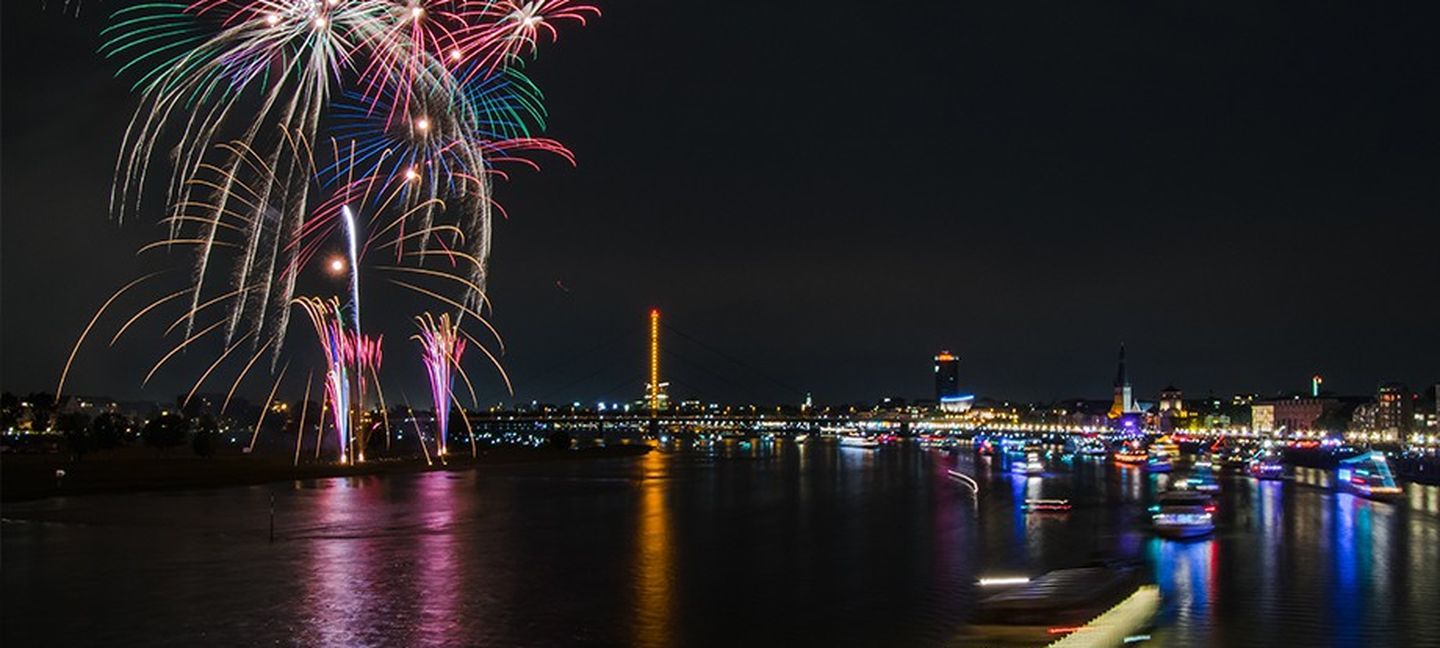 In bunten Farben explodierendes Feuerwerk über dem nächtlichen Rhein in Düsseldorf.