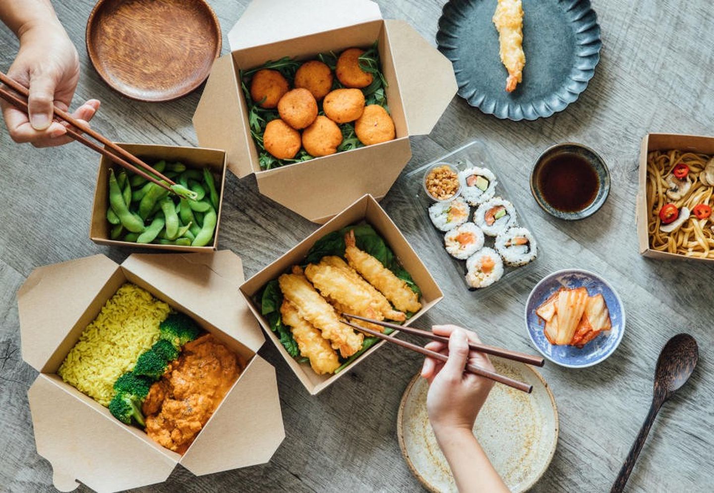 Ein Tisch mit geliefertem Essen in Einwegverpackungen aus Pappe und Kunststoff. 