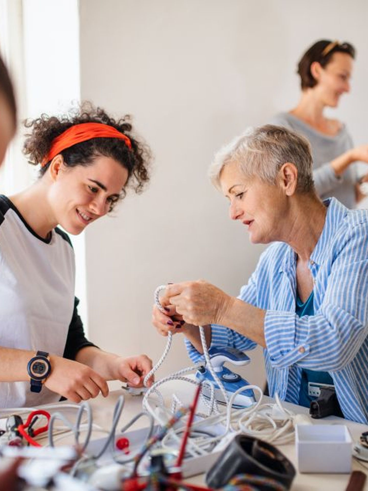 Eine Gruppe von Personen unterschiedlichen Alters widmet sich der Reparatur verschiedener Geräte. © Halfpoint Images / Moment via Getty Images 
