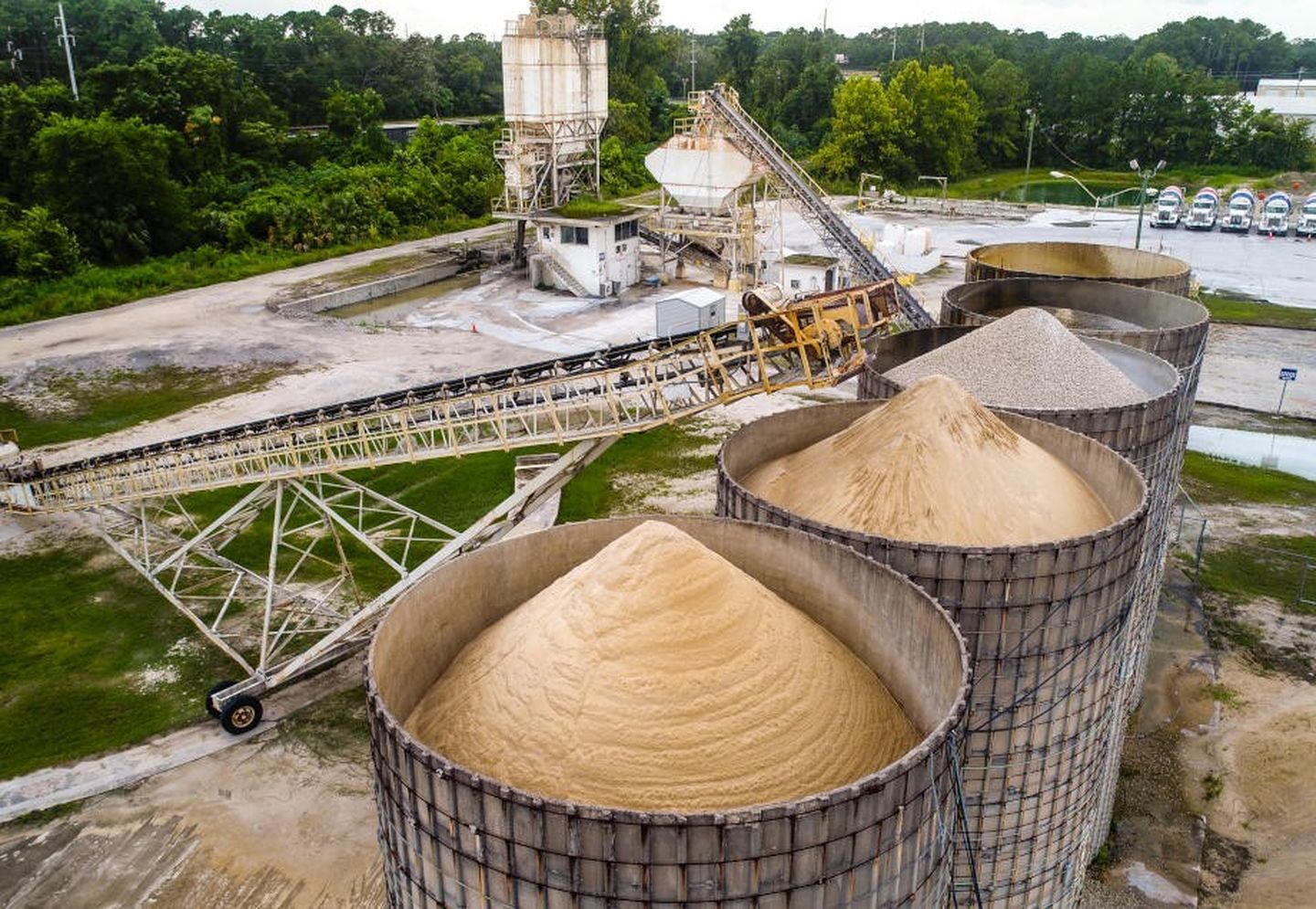 Die Luftaufnahme einer Zementfabrik zeigt Förderbänder, Silos und Lastwagen.