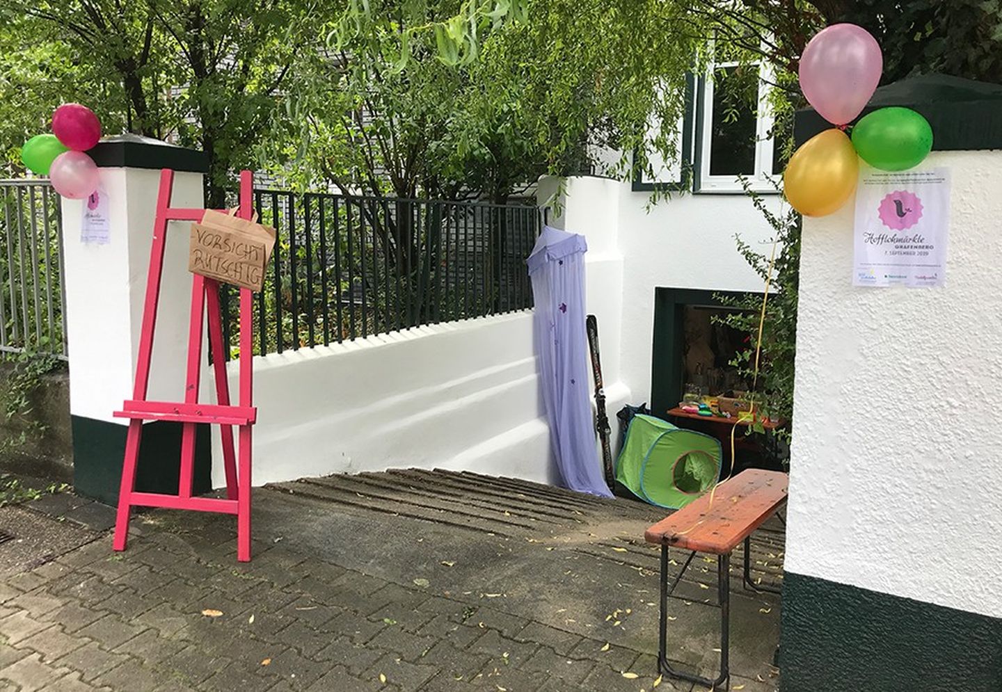 Garageneinfahrt geschmückt mit bunten Ballons, pinkfarbener Staffelei, lilafarbenem Betthimmel, grünem Krabbeltunnel. 