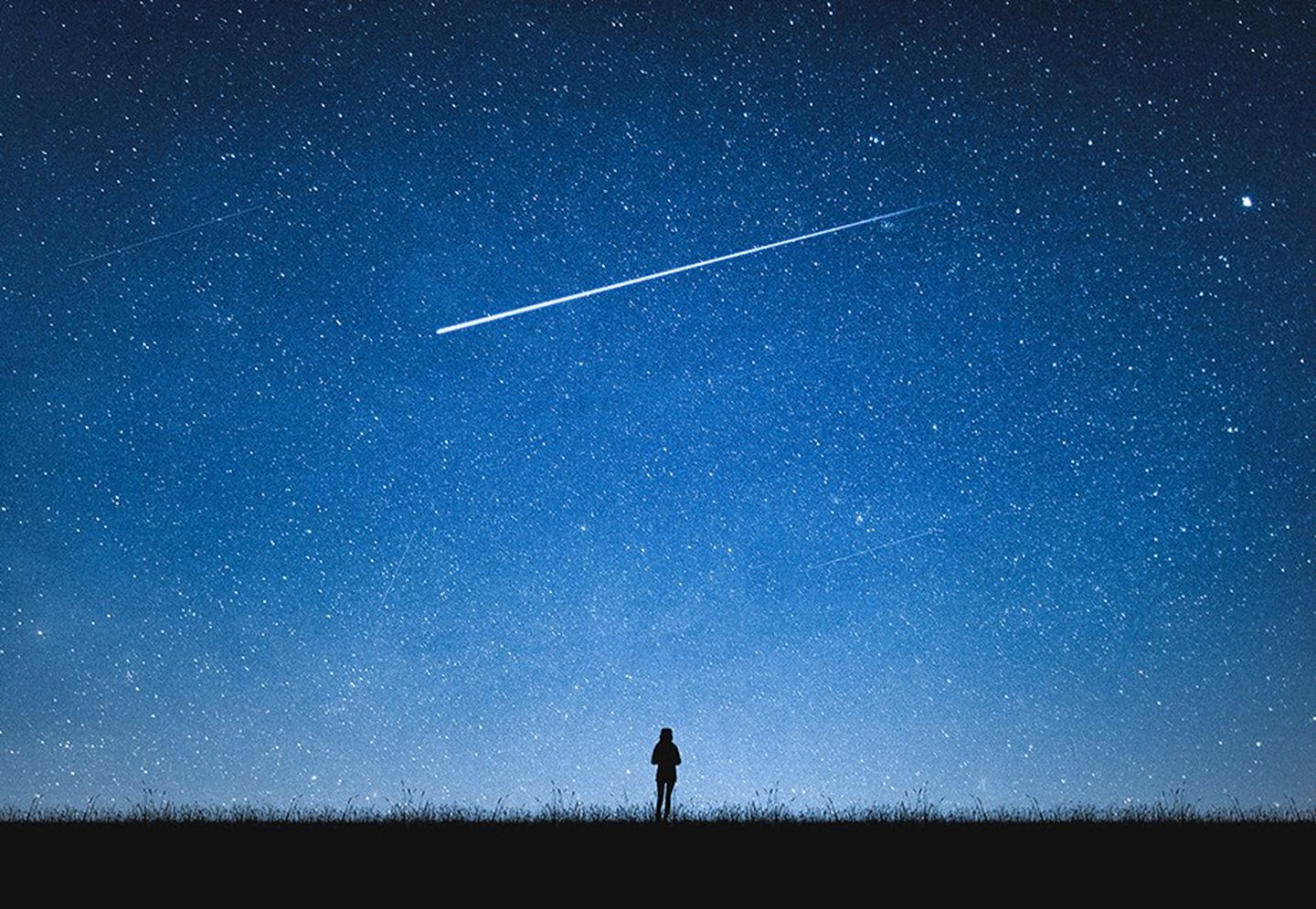 Eine einzelne Person unter einem Nachthimmel voller Sterne.
