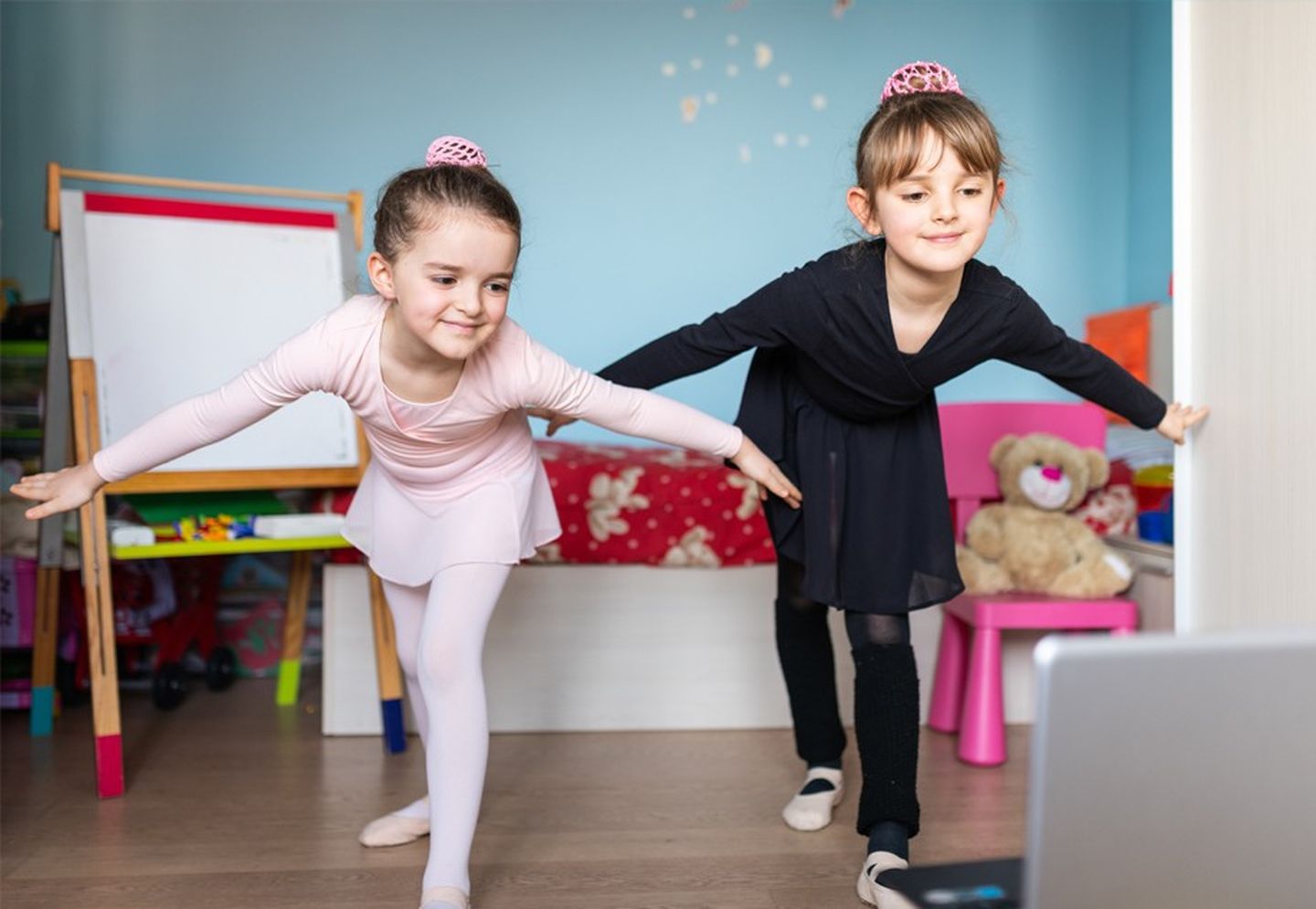 Zwei junge Mädchen tanzen Ballett – die Trainerin auf dem Laptop macht es vor.