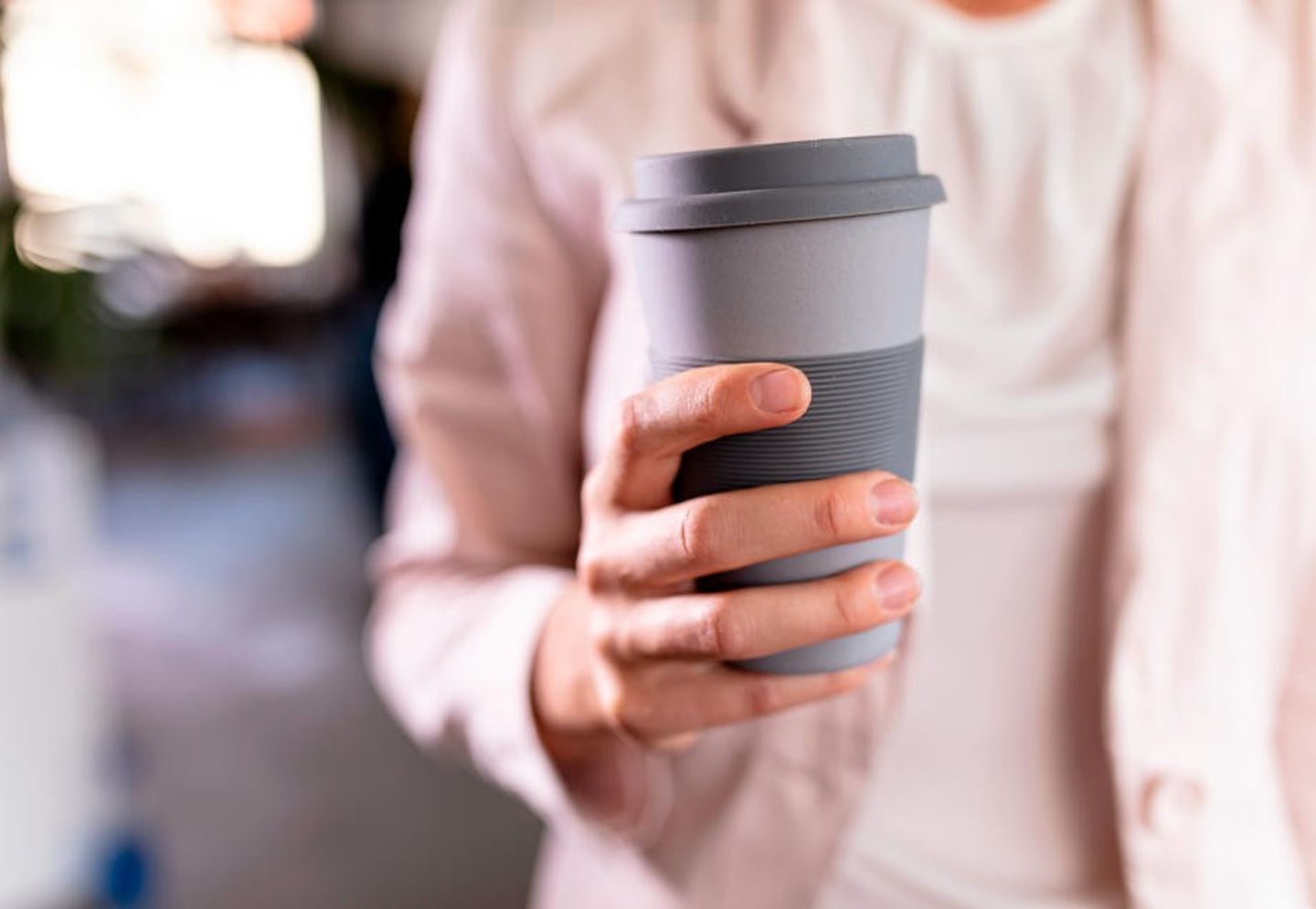 Eine Frau hält einen Mehrwegbecher aus recycelbarem Kunststoff. 