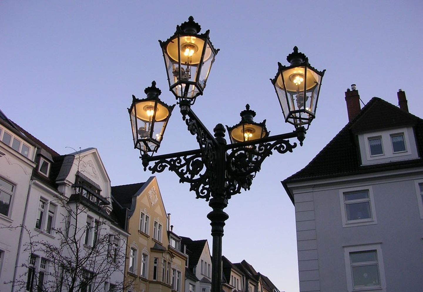 Eine aus Gusseisen gefertigte, vierarmige Gaslaterne in Betrieb.