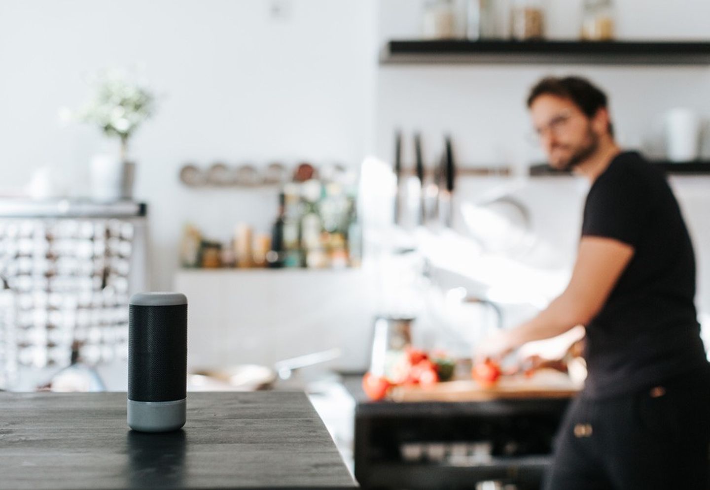 Ein Mann bei der Küchenarbeit ruft seinem Sprachassistenten zu.