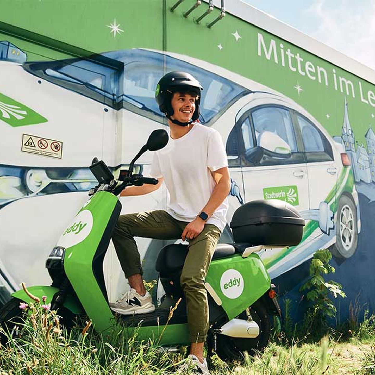 Ein E-Roller mit Mann vor einem Traffohäuschen der Stadtwerke Düsseldorf