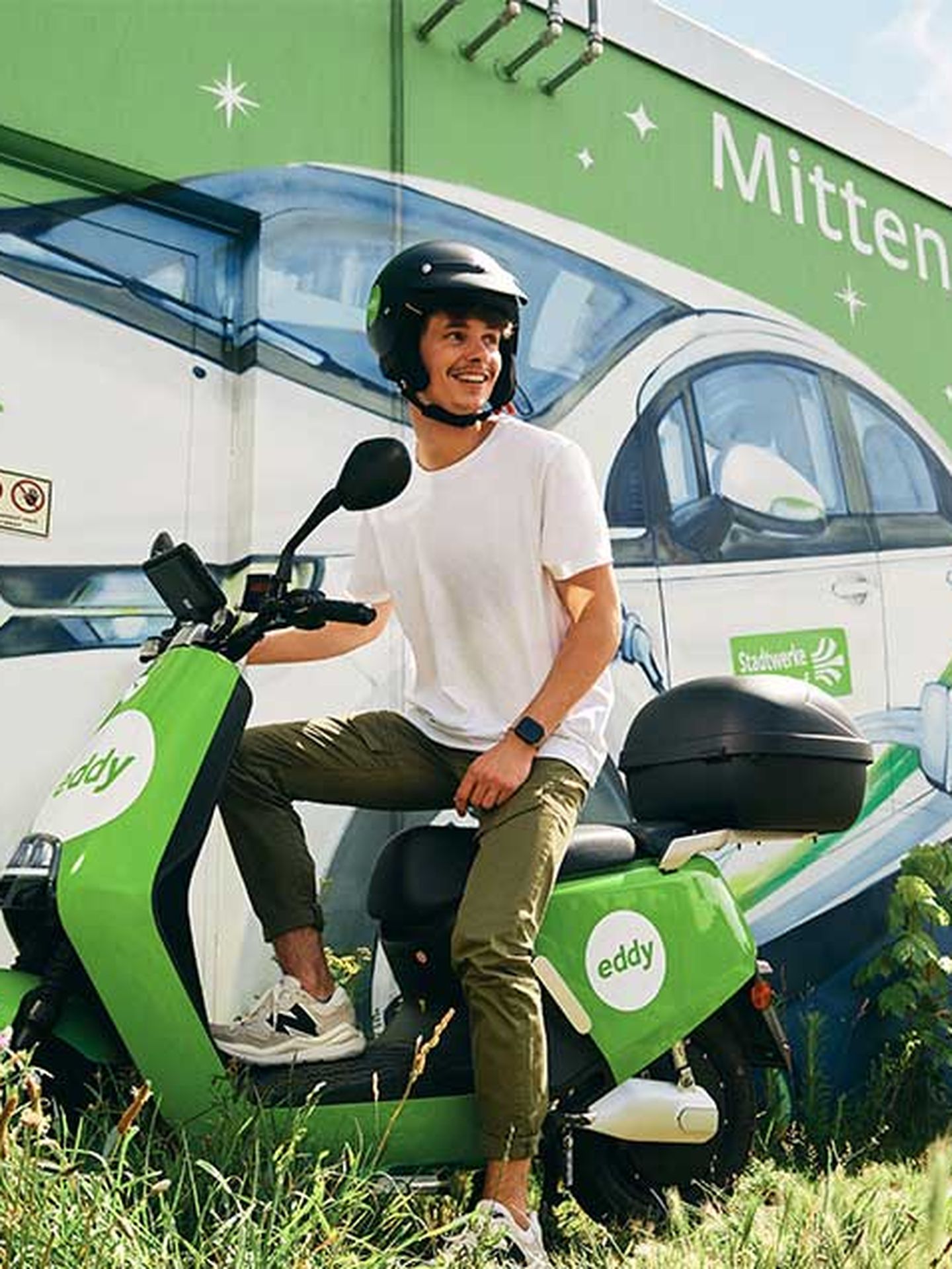 Ein E-Roller mit Mann vor einem Traffohäuschen der Stadtwerke Düsseldorf