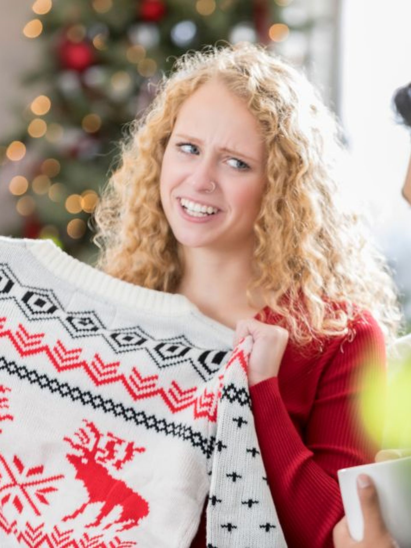 Schrottwichteln: Frau hält skeptisch ihren erwichtelten Weihnachtspullover