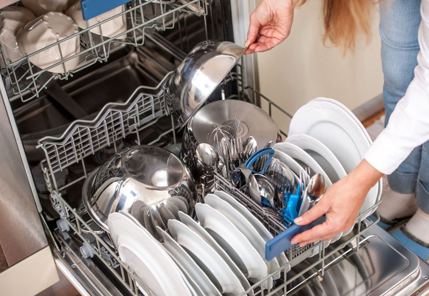 Spülmaschine einräumen: Eine Frau belädt den unteren Geschirrkorb mit einer großen Schüssel.
