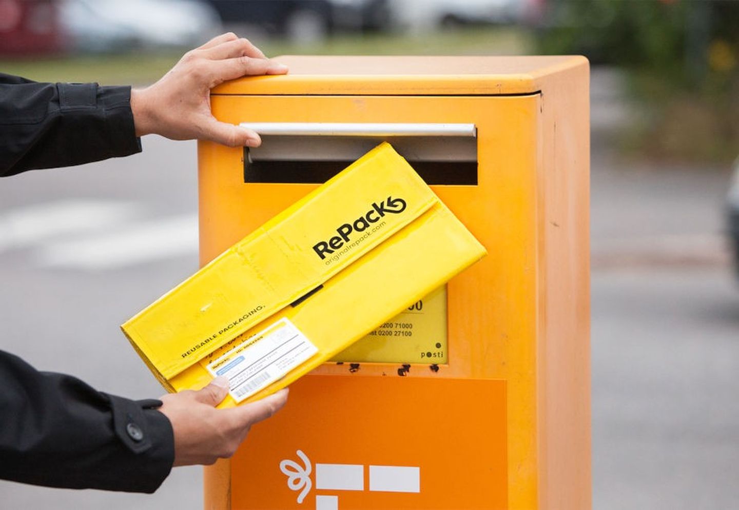 Mann wirft wiederverwendbaren Versandtasche in den Briefkasten.