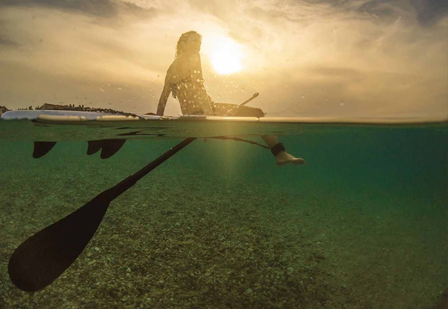 Frau sitzt auf einem SUP-Board.